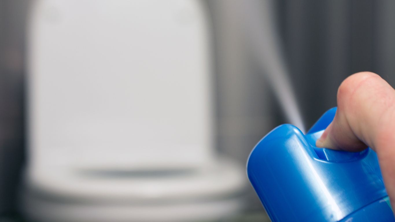 Don’t Mask It Fix It with Real Odor Removal Solutions Hand spraying air freshener in bathroom as a temporary odor removal method.