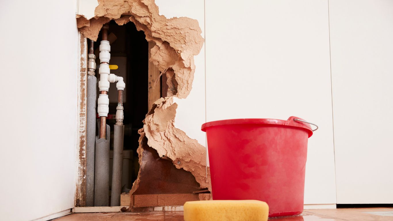 Water damage to drywall revealing plumbing pipes in need of repair for water damage restoration in Detroit.